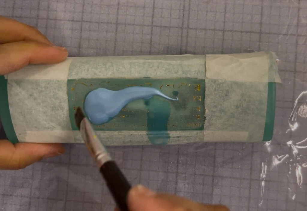 Application de la première couche de base de peinture acrylique de manière uniforme sur une boîte à lunettes optiques avec un pinceau plat
