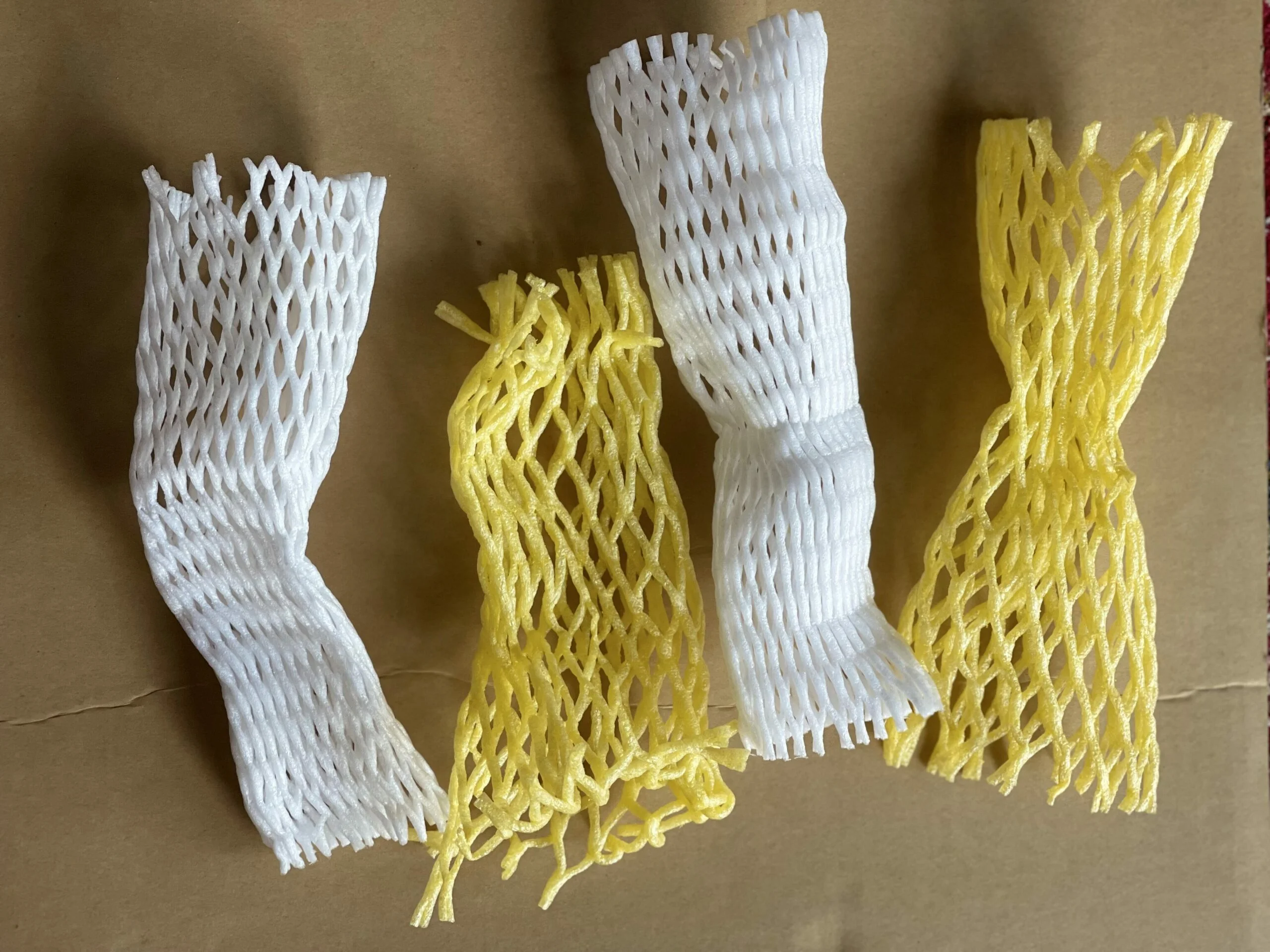 Matériaux disposés pour fabriquer une fleur de Kadam : emballages en mousse plastique blanche et jaune, ciseaux, fil, branche, papier crépon vert et ruban floral