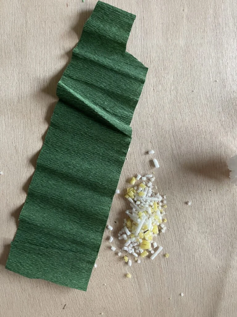 Green crepe paper cut into leaf shapes and arranged along the branch