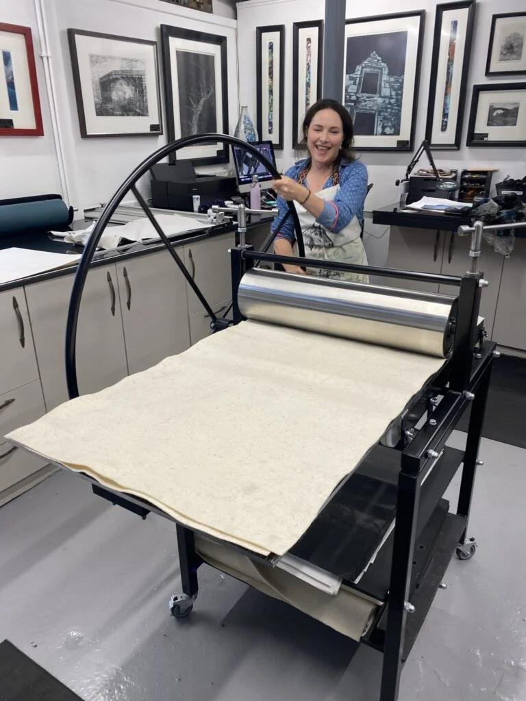 Etching press with heavy rollers used to transfer ink from metal plate to paper
