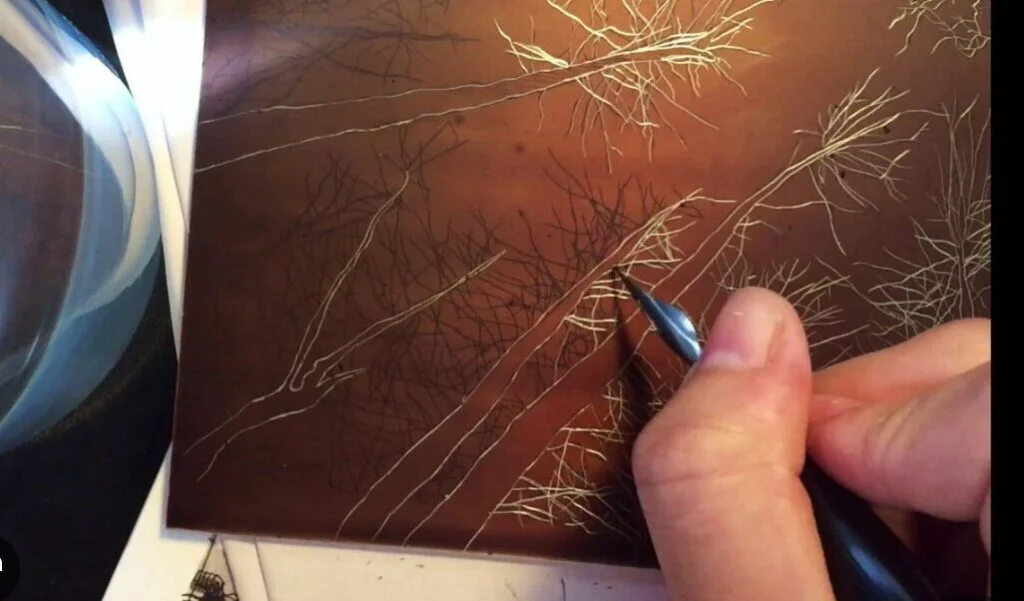 Drawing a design into the acid-resistant ground on a metal plate using an etching needle